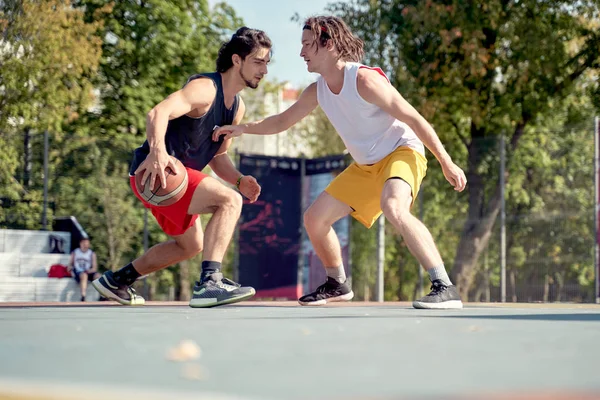 Фото двух спортсменов, играющих в баскетбол на детской площадке в летний день . — стоковое фото