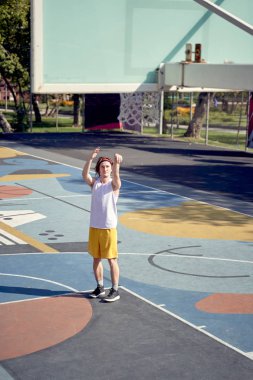 Atlet adamın oyun alanında basketbol potasına top atarken çekilmiş tam uzunlukta fotoğrafı.