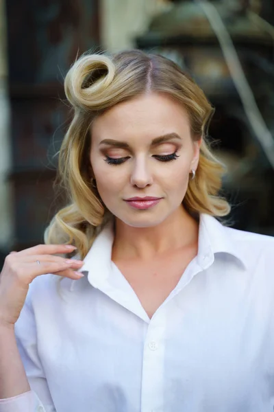 Foto de la joven rubia con los ojos cerrados en camisa blanca en la calle — Foto de Stock