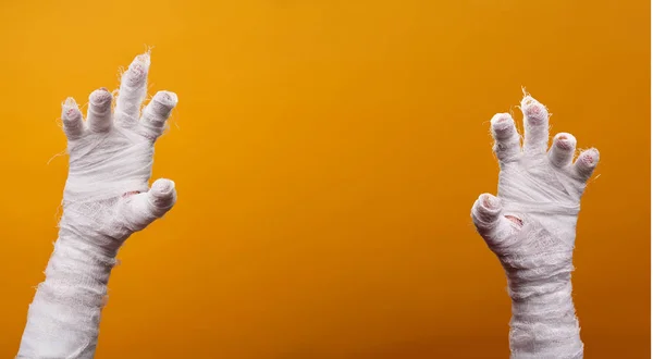 Foto de duas mãos múmias no fundo laranja vazio  . — Fotografia de Stock