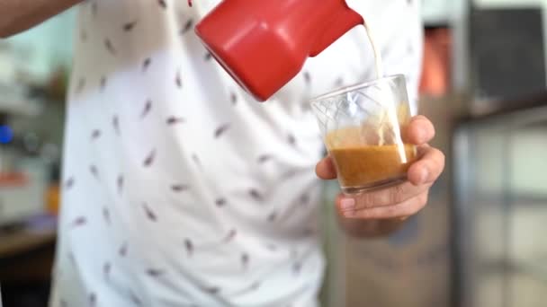 Barista håller glas med kaffe i hand och häller mjölk — Stockvideo