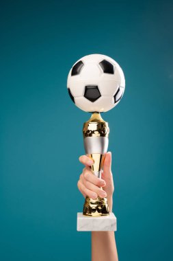 Boş mavi arka plan üzerinde futbol topu ile el tutma fincan görüntü