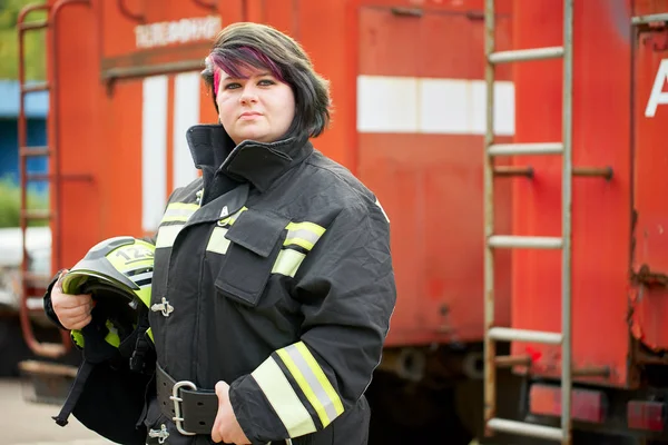 Obraz brunetka strażak stoi obok strażaków samochodu. — Zdjęcie stockowe