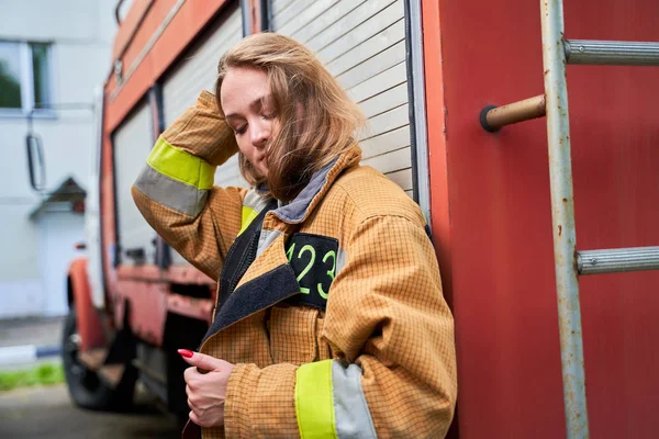 Gambar gadis pemadam kebakaran di sebelah mesin api di jalan  . — Stok Foto