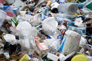 Sokakta bir sürü çöp torbası ve plastik şişe var.