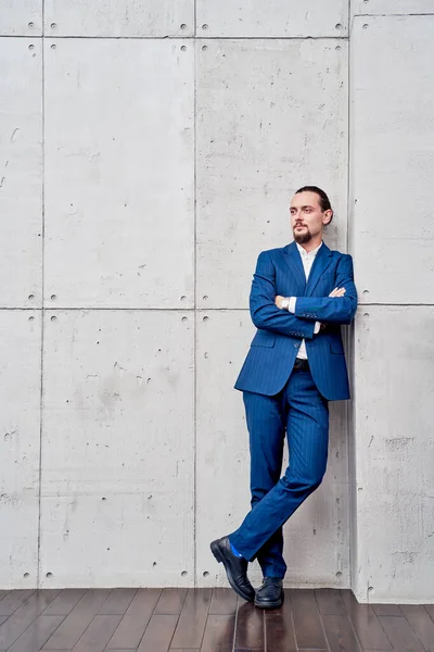 Full-length photo of young brunet in business suit with arms crossed standing near concrete wall — Stock Photo, Image