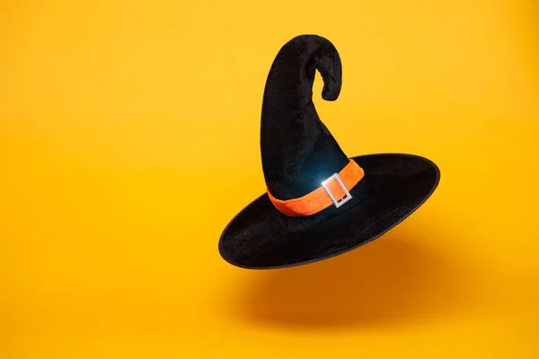 Černá čarodějnice klobouk na prázdném oranžovém pozadí. — Stock fotografie