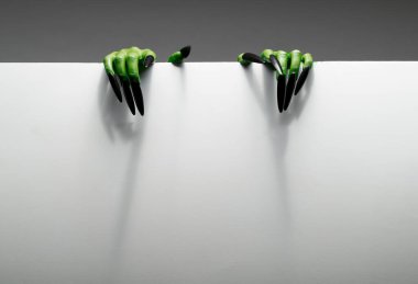 Two green hands are holding blank sheet of paper against grey background. clipart
