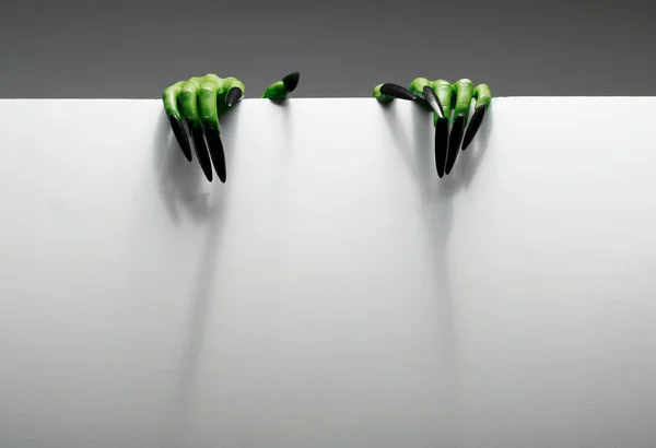 Dos manos verdes sostienen una hoja de papel en blanco sobre un fondo gris . —  Fotos de Stock