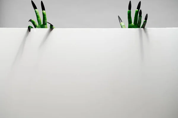 Dwie zielone ręce trzyma pusty arkusz papieru na szarym tle w studio — Zdjęcie stockowe