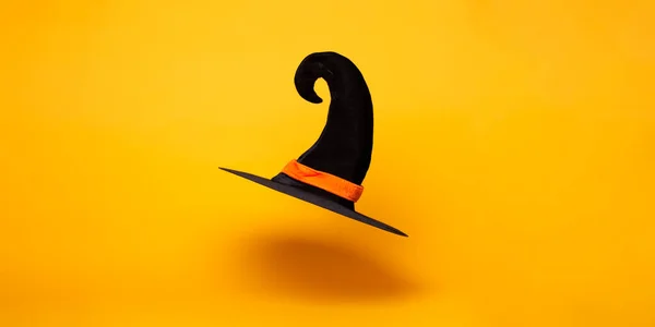 Sombrero de bruja negro sobre fondo naranja en blanco, espacio para texto . —  Fotos de Stock