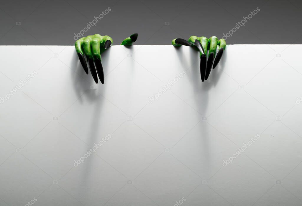 Two green hands are holding blank sheet of paper against grey background.