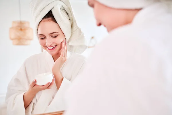 Zdjęcie szczęśliwej kobiety w szlafroku i z ręcznikiem na głowie odbitym w lustrze. — Zdjęcie stockowe