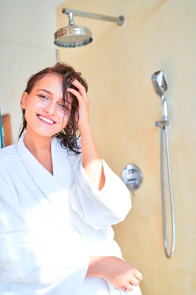 Foto di felice bruna con i capelli bagnati in accappatoio bianco in piedi in bagno . — Foto Stock