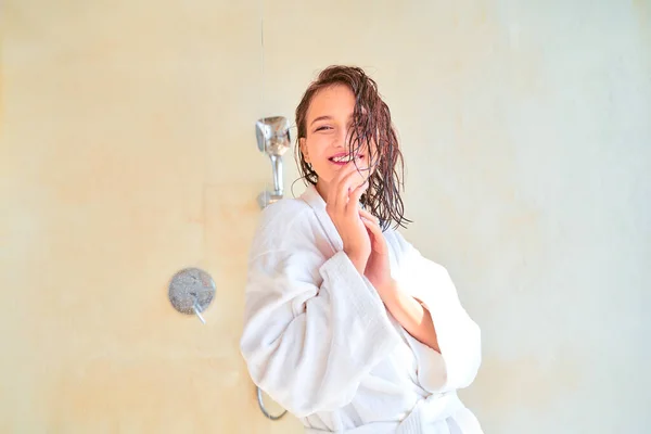 Imagem da mulher morena feliz com cabelo molhado em roupão de banho branco em pé na banheira , — Fotografia de Stock
