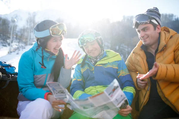 Mulher sorridente e homem de capacete com mapa nas mãos no resort de neve no dia de inverno — Fotografia de Stock