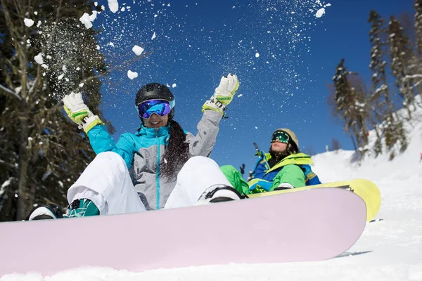 Donna in casco gettando neve seduta accanto all'uomo sulla collina . — Foto Stock