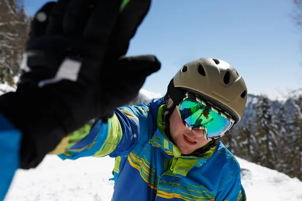 Ritratto di uomo sportivo in casco e maschera che fa stretta di mano in località montana . — Foto Stock