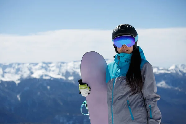 Mulher de capacete e máscara com snowboard na estância de esqui no inverno . — Fotografia de Stock