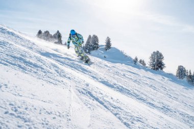 Kışlık tatil köyünde kask giyen genç sporcunun görüntüsü.