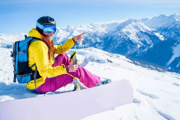 Foto lateral de mujer deportiva con mapa en sus manos y snowboard sentado en la ladera nevada . —  Fotos de Stock