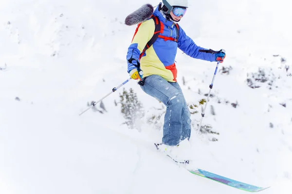 Foto de un deportista en chaqueta multicolor esquiando —  Fotos de Stock