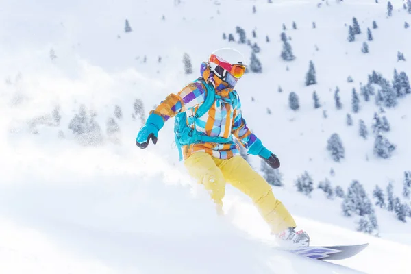 Joven chica deportiva en casco y máscara está montando en snowboard en la pendiente nevada en el día de invierno . —  Fotos de Stock