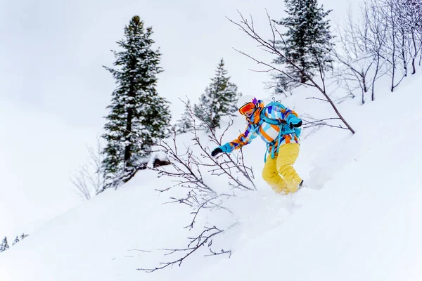 Athletin mit Helm und Maske fährt auf Snowboard auf schneebedeckter Piste — Stockfoto