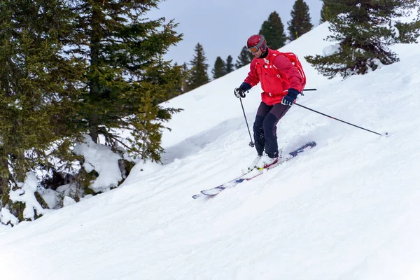 Foto laterale dell'uomo sportivo in giacca rossa e con zaino da sci nella località invernale — Foto Stock