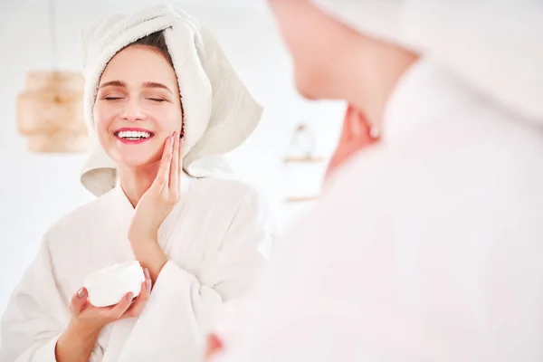 Imagem da jovem mulher em roupão de banho e com toalha na cabeça refletida no espelho — Fotografia de Stock