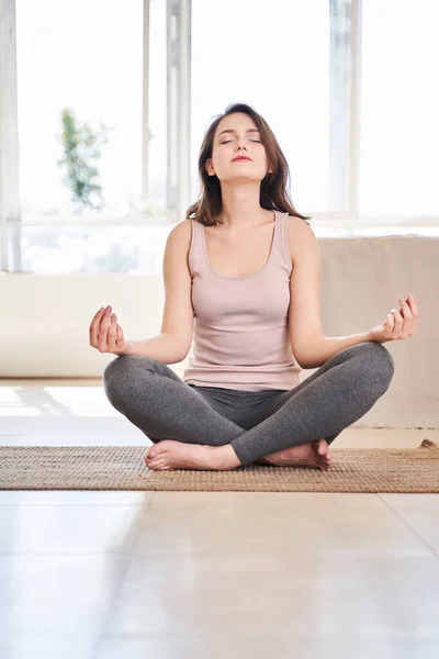 Photo of young brunette sitting in lotus position in bathroom kamat in apartment. — Stock Photo, Image