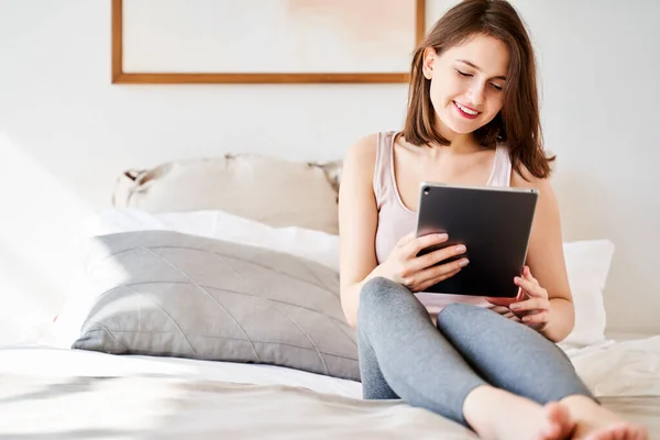 Foto de mujer con la tableta en las manos sentada en la cama  . —  Fotos de Stock