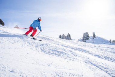 Kasklı ve maskeli bir adam karlı yamaçta kayak yapıyor. .