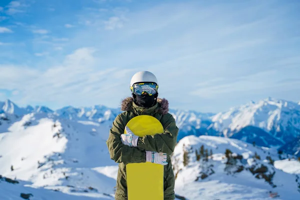 Foto de hombre en casco con tabla de snowboard de pie en el complejo de nieve  . —  Fotos de Stock