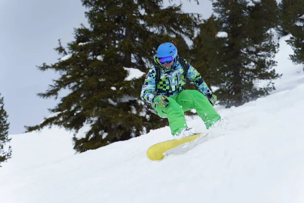 Man snowboardåkare ridning på bergssluttningen på bakgrund av träd . — Stockfoto