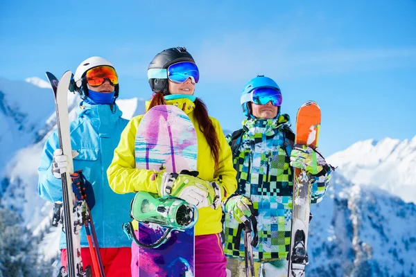 Photo of sports woman and men with skis and snowboard standing at ski resort at afternoon — Stock Photo, Image