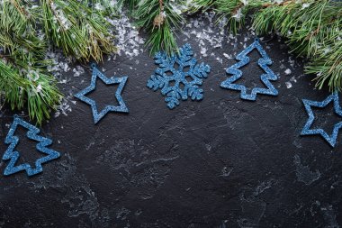 Ladin dalları, siyah arka planda mavi Noel süslemeleri oyuncakları