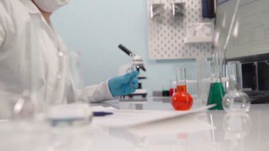 Kadın bilim adamı cam plakadan plastik kutuya numunelerle analiz malzemesi alıyor. Bilim, biyoteknoloji, sağlık ve kimya konsepti.