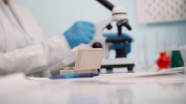 Kadın bilim adamı cam plakadan plastik kutuya numunelerle analiz malzemesi alıyor. Bilim, biyoteknoloji, sağlık ve kimya konsepti.