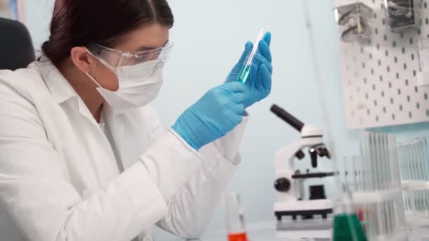 検査管内の液体を分析する女性医師。科学、バイオテクノロジー、医療、化学の概念. — ストック動画