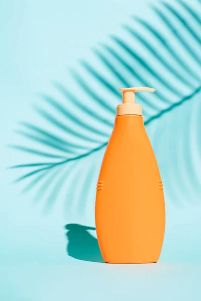 Orange container for lotion without label on blue background — Stock Photo, Image