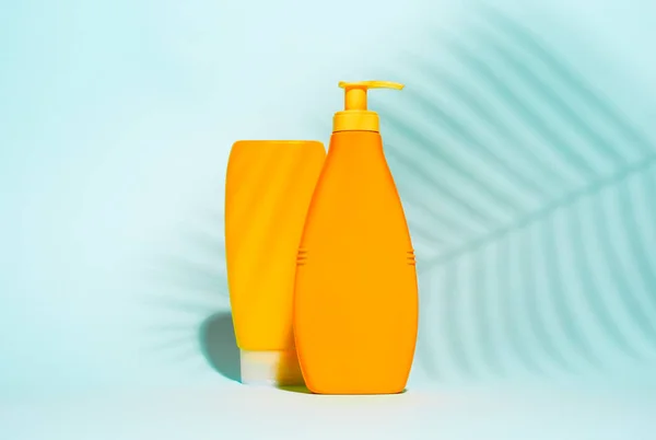 Orange containers for lotion without label on blue background with leaf — Stock Photo, Image