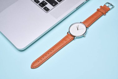 Kol saati, boş mavi arkaplanda dizüstü bilgisayar