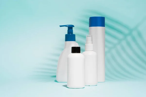 Bílé nádoby na sprej, tekuté mýdlo na čistě modrém pozadí — Stock fotografie