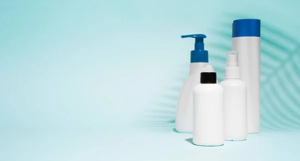 Contenitori bianchi senza etichette per spray, sapone liquido su fondo blu pulito — Foto Stock