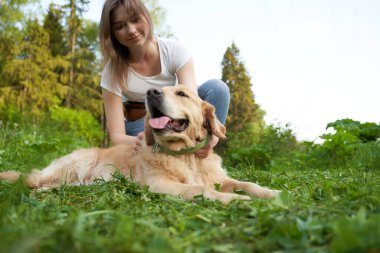 Mutlu kadın, yürürken köpeğinin yanında çömeliyor.