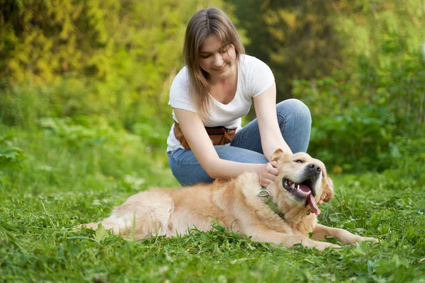 Mladá žena dřepí vedle psa při chůzi — Stock fotografie