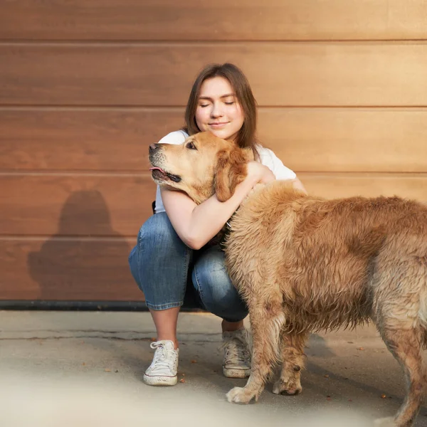 Žena v modrých džínách objímající psa venku odpoledne . — Stock fotografie