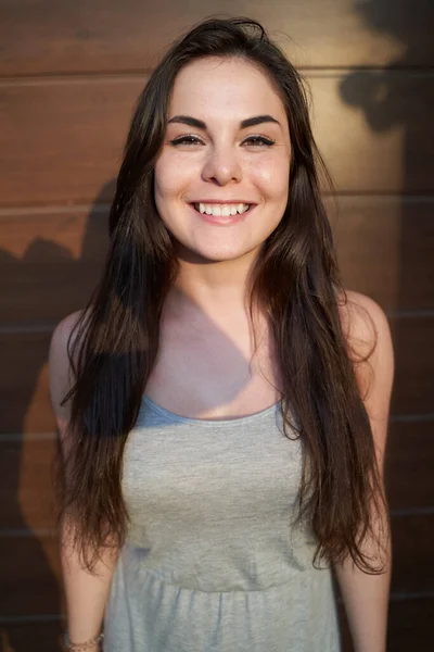 Ragazza sorridente guardando la fotocamera contro il muro marrone in strada — Foto Stock