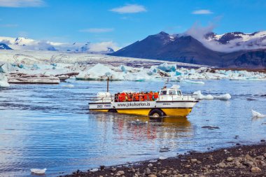 Shore, buz lagün, Jokulsarlon, İzlanda günbatımında yaklaşan turistlerin büyük motorlu tekne.
